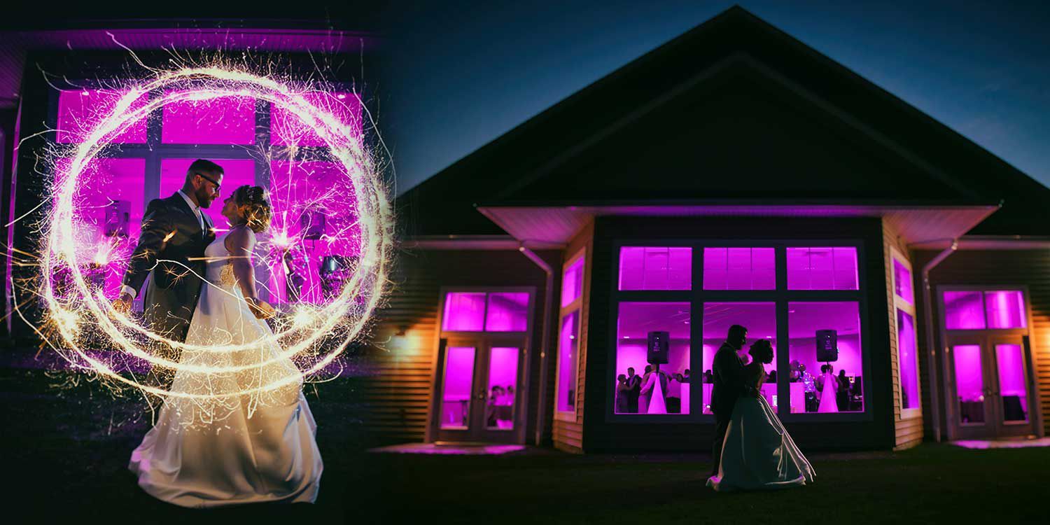 A bride and groom are standing with sparklers and sunset at The Lake House wedding photography by Connecticut Wedding Photographers Rogers Photography.