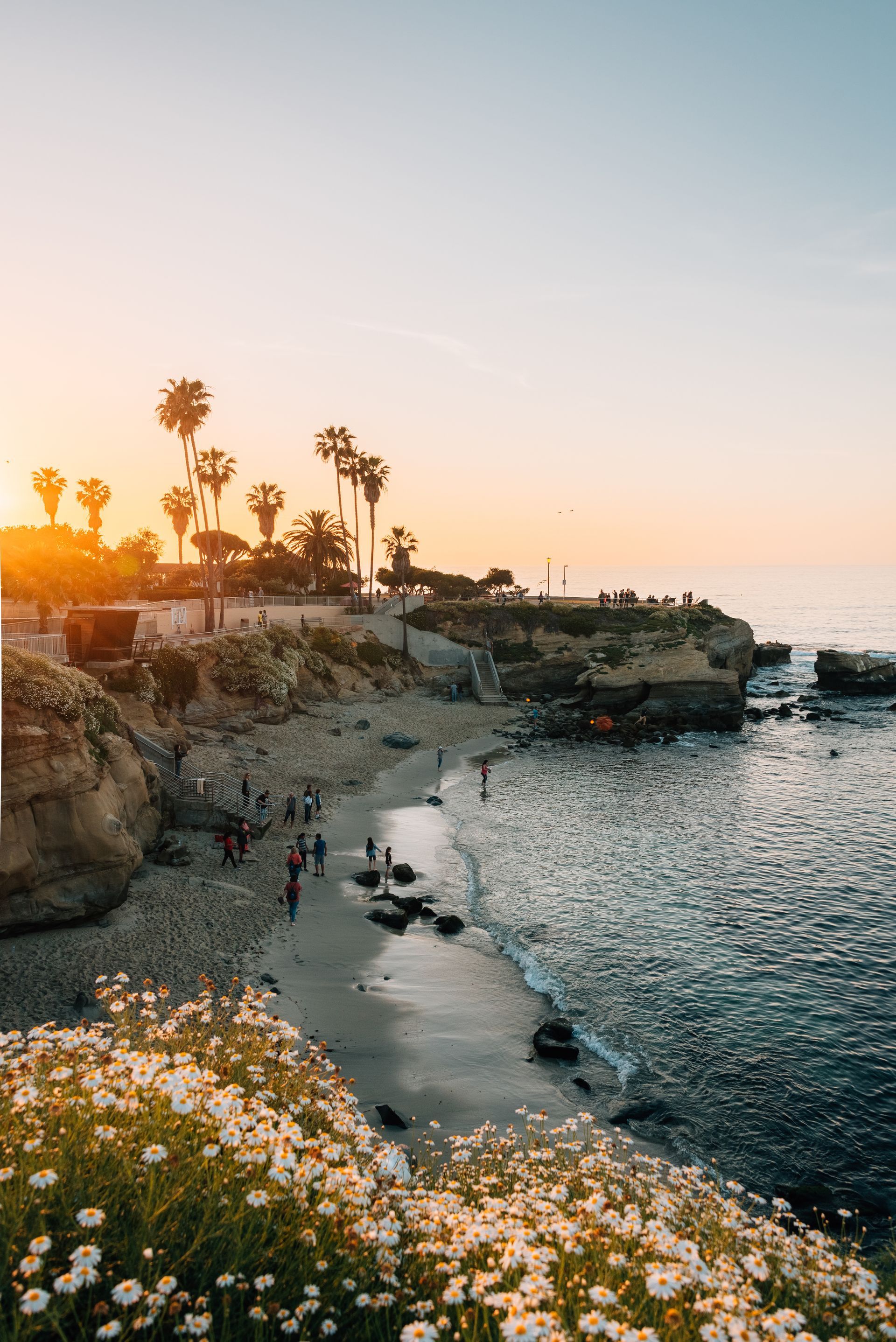 A group of people are walking on a beach at sunset.