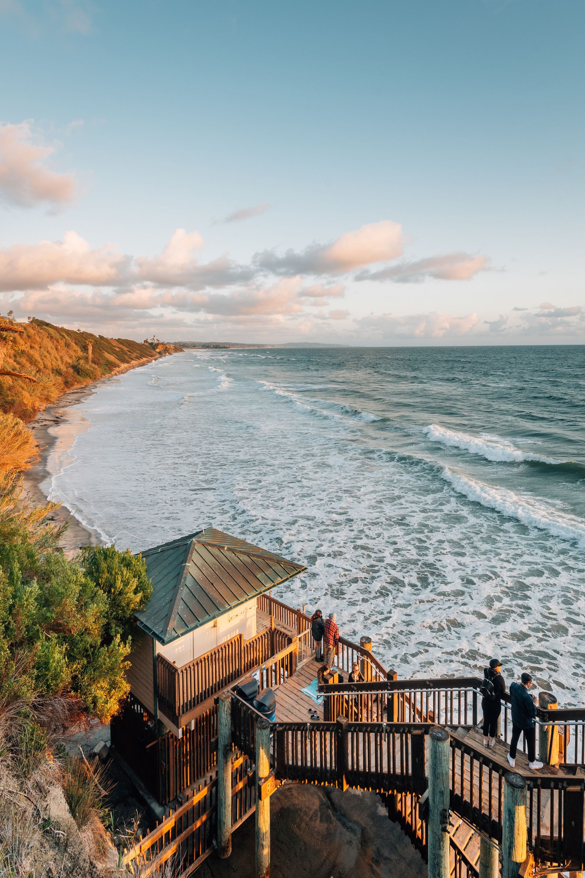 A group of people are standing on a pier overlooking the ocean.