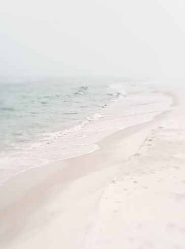 A blurred image of a beach with waves coming in on a cloudy day.