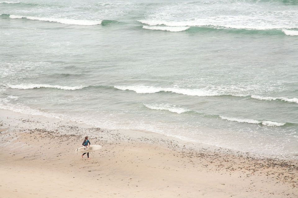 A person is standing on a beach holding a surfboard.