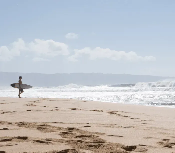 A man is carrying a surfboard on the beach