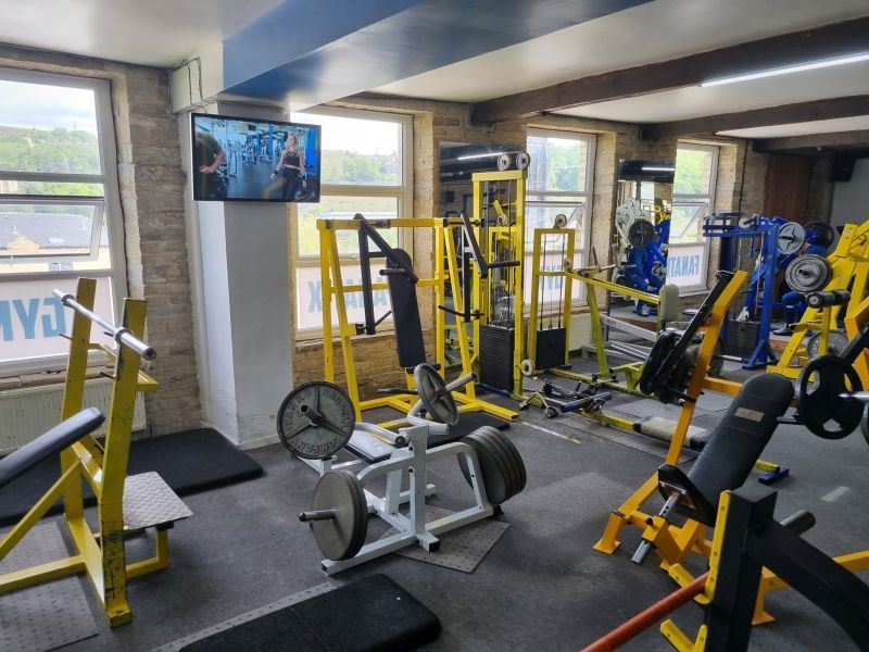 a gym with a lot of exercise equipment and a television on the wall
