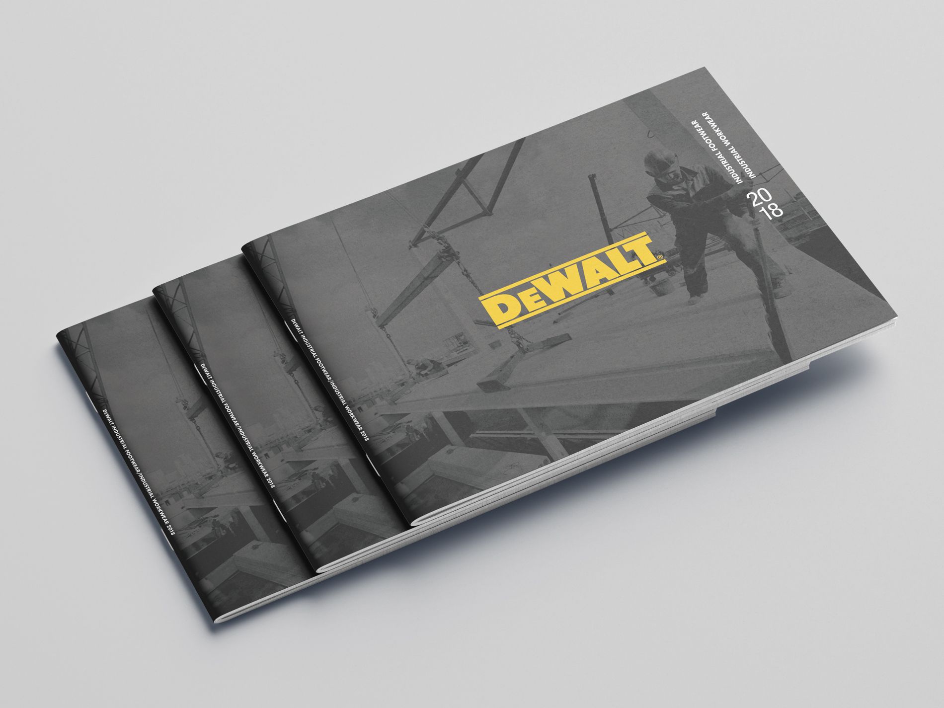 Stacked DeWalt product catalogs. The top cover has the DeWalt logo and a construction worker silhouetted in yellow.