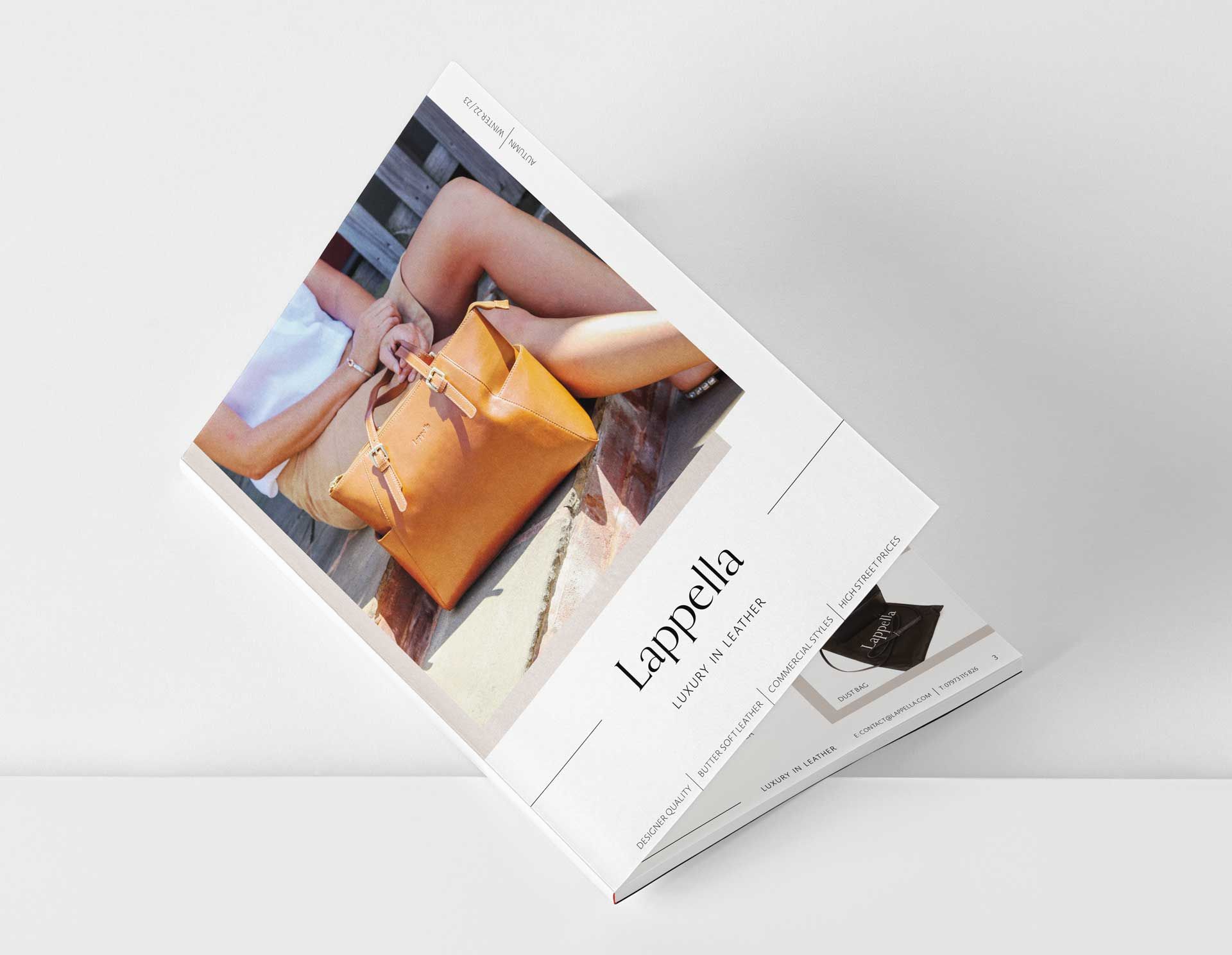 Tan leather handbag on lap of person sitting outside. Lappella logo.