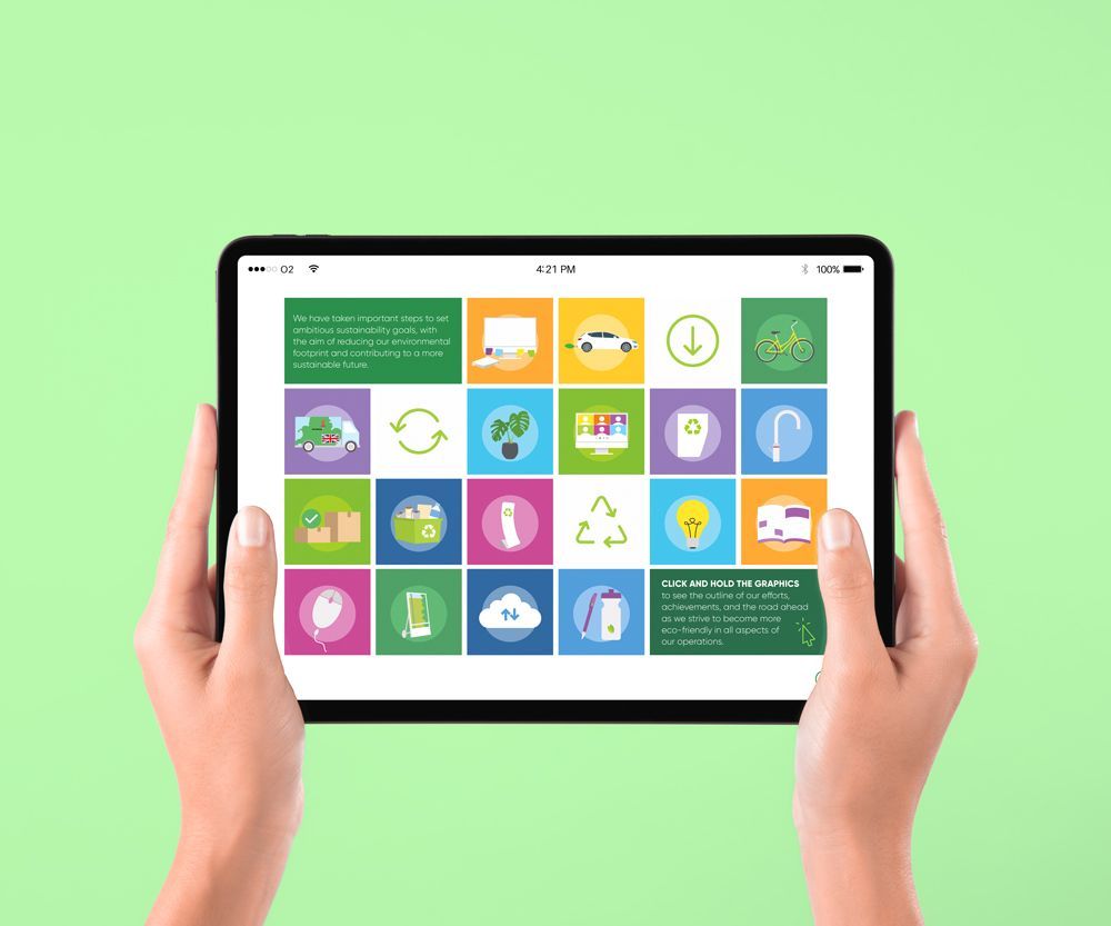 Hands holding tablet displaying colorful recycling icons on a green background.