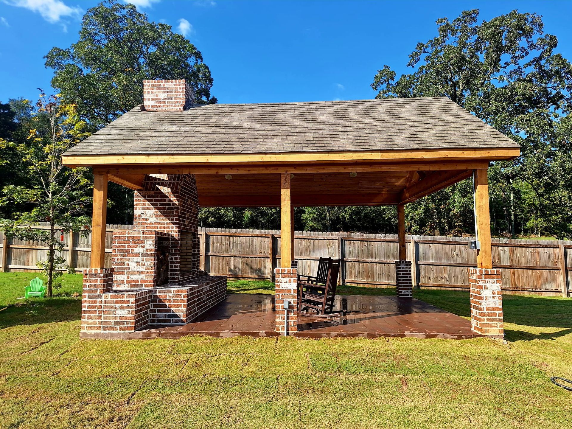 Outdoor brick fireplace and gazebo on a grassy lawn. The roof has a wood-like texture.