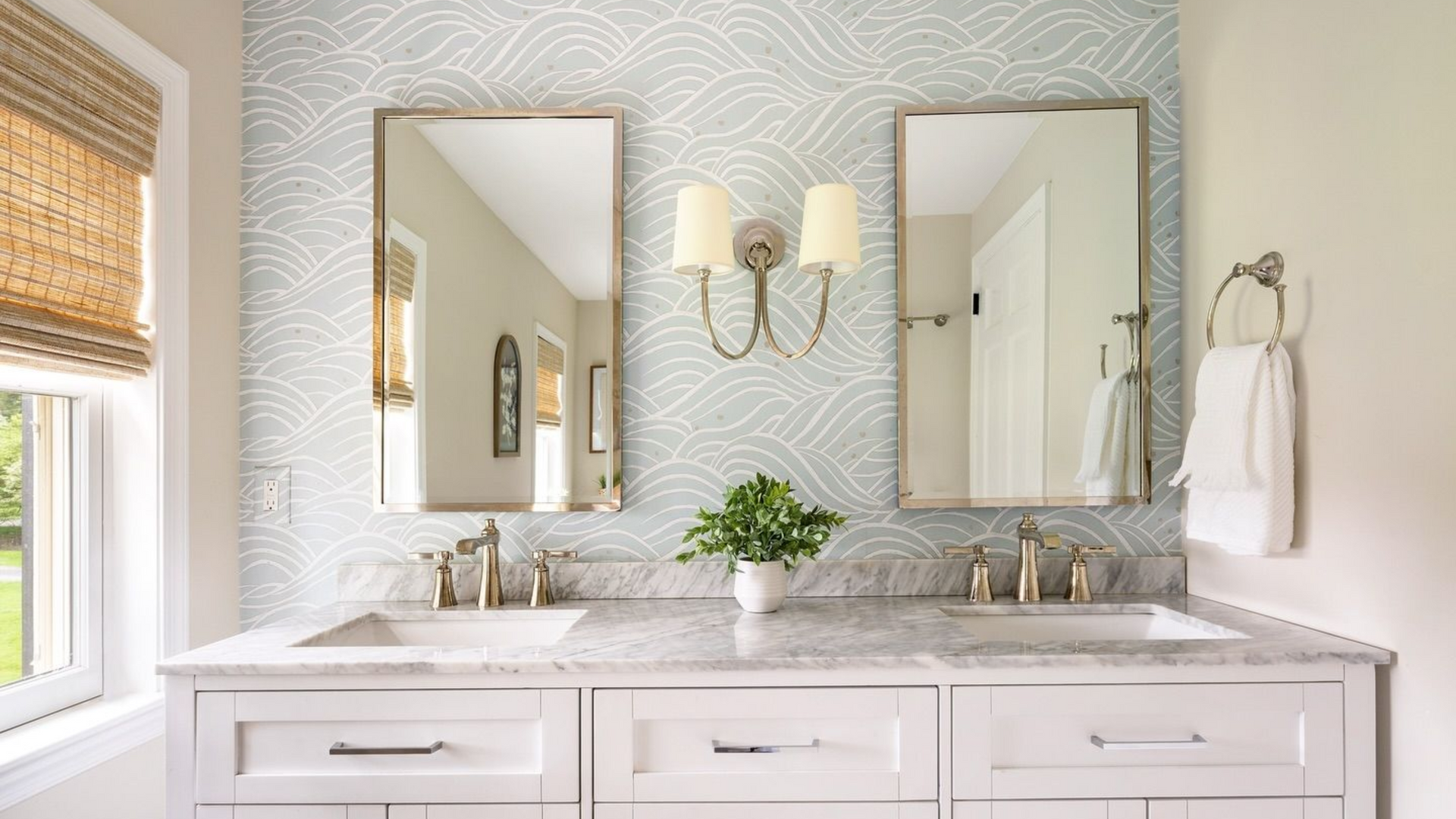 White bathroom with double vanity, patterned wallpaper, and gray herringbone floor.