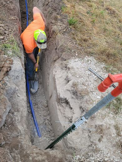 A man is digging a hole in the ground with a shovel and a saw.