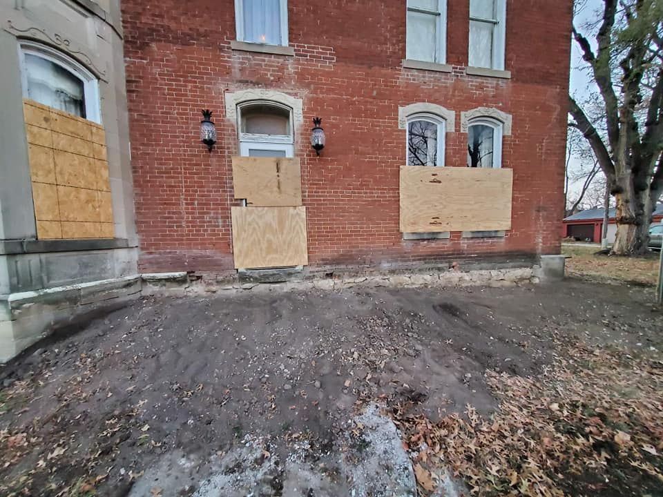 A brick building with a lot of windows boarded up.