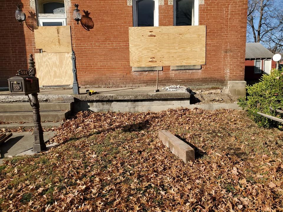 A brick house with a wooden board on the window.