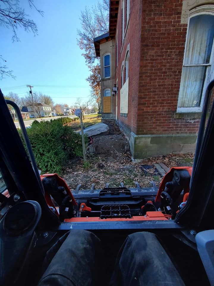 A person is sitting in a vehicle in front of a brick building.