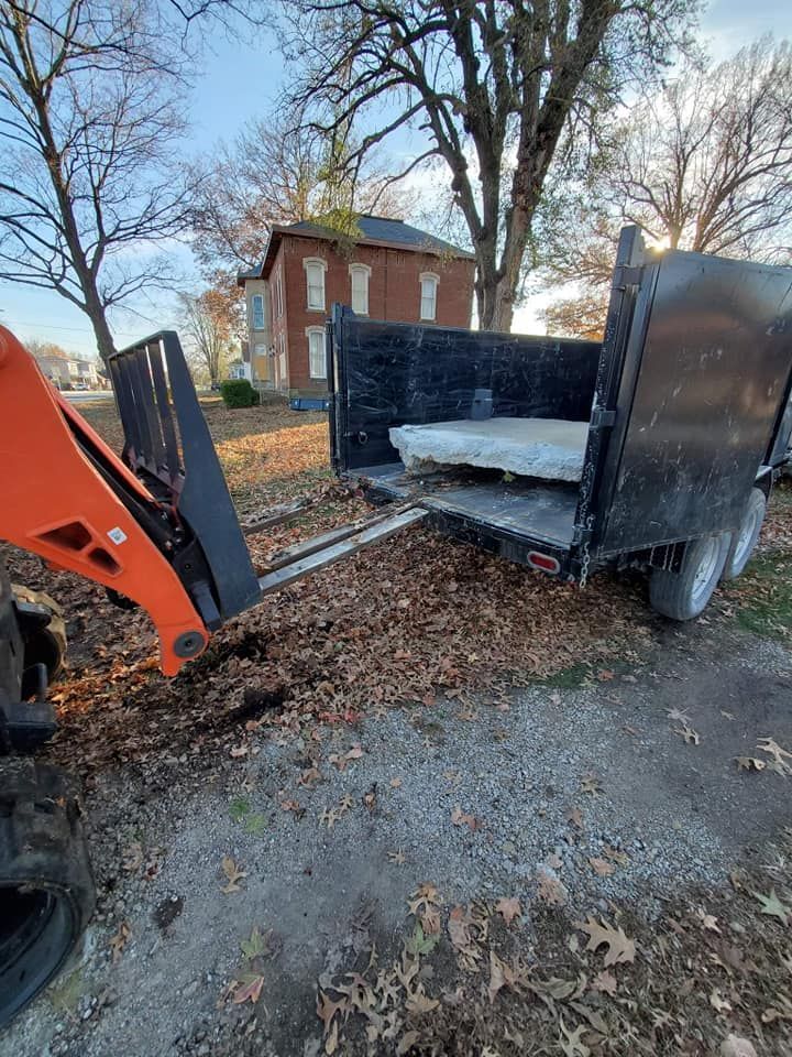 A trailer is being towed by a tractor on a dirt road.