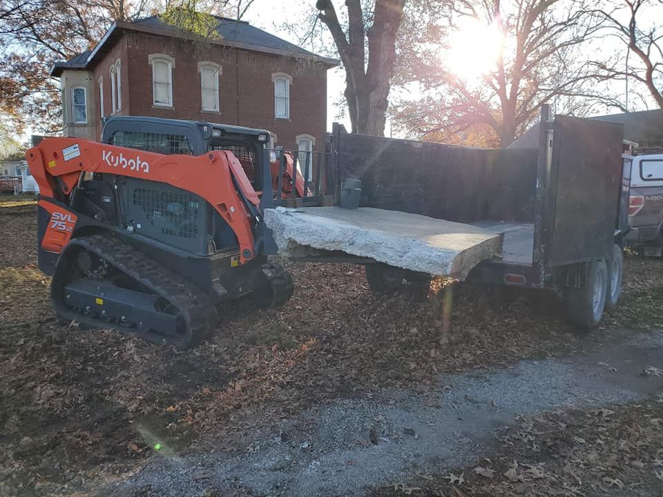 A kubota bulldozer is parked next to a dump truck.