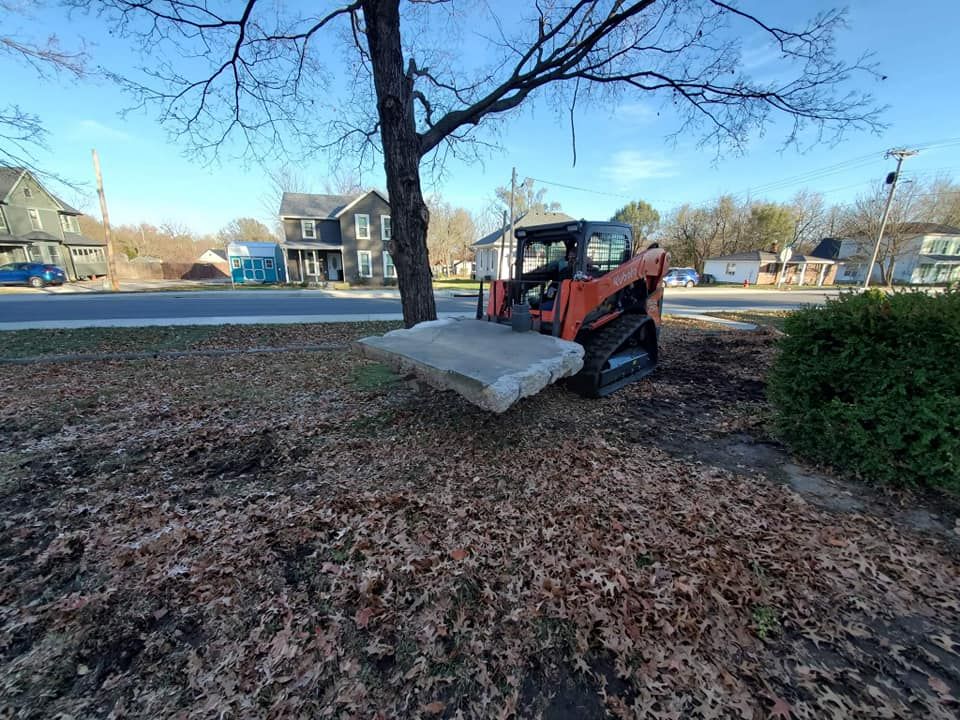 A bulldozer is sitting on top of a pile of leaves next to a tree.