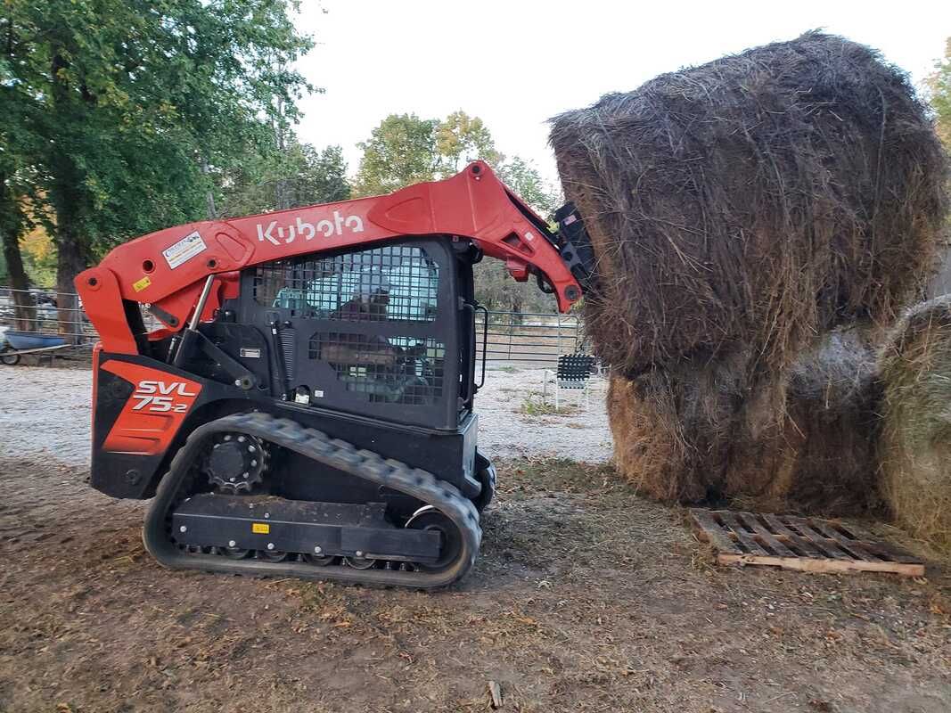 A bulldozer is loading hay into a bale.