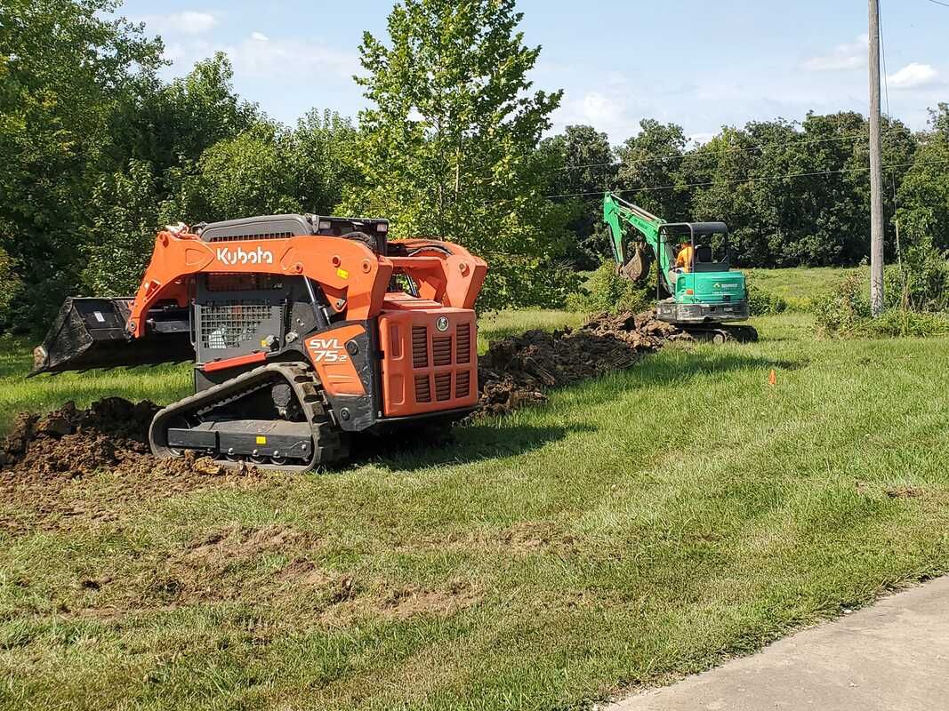A bulldozer is sitting in the grass next to a green excavator.