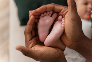 Una persona sostiene los pies de un bebé en sus manos.