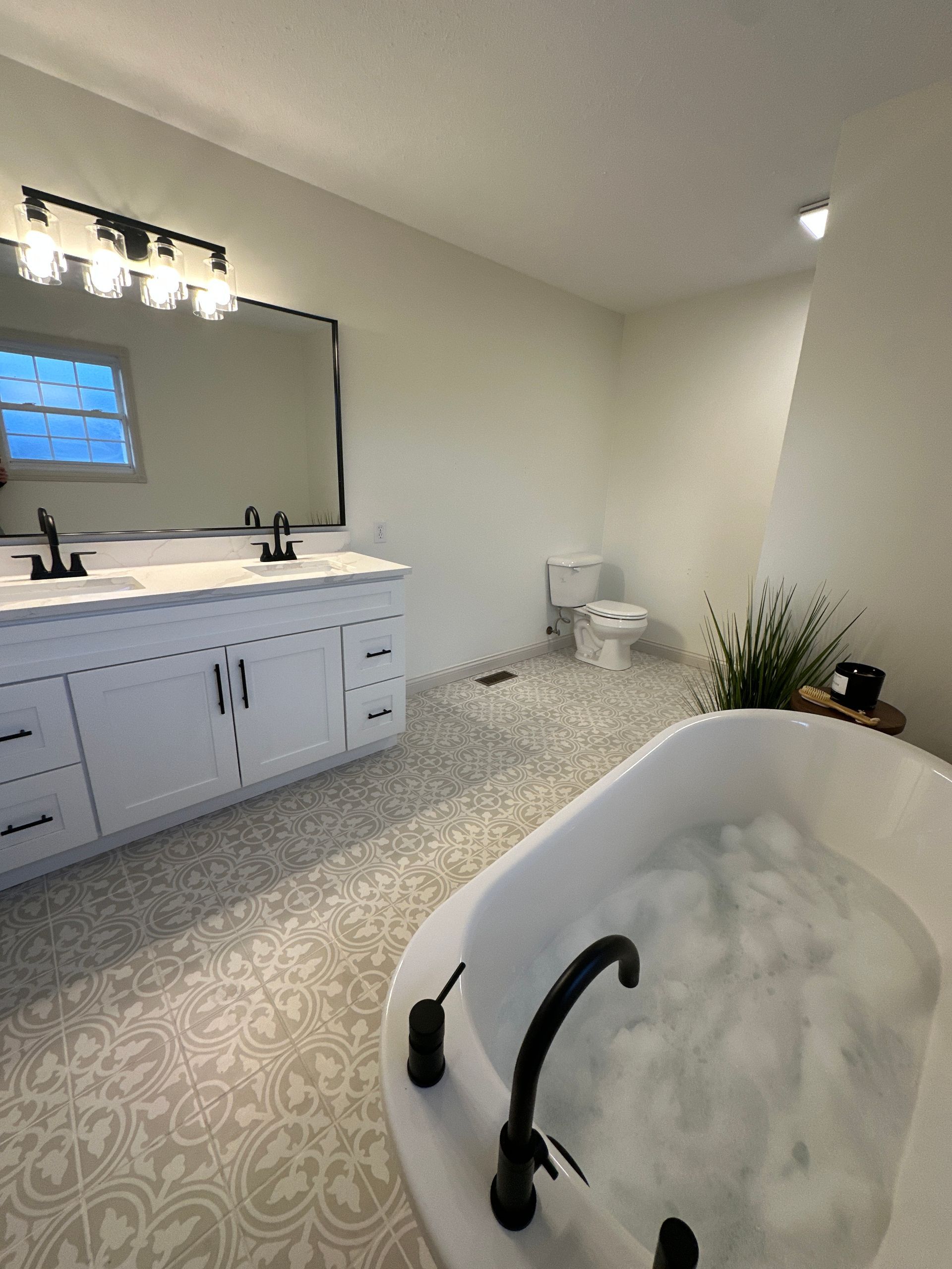 Modern white bathroom with soaking tub, dual vanity, and patterned tile.