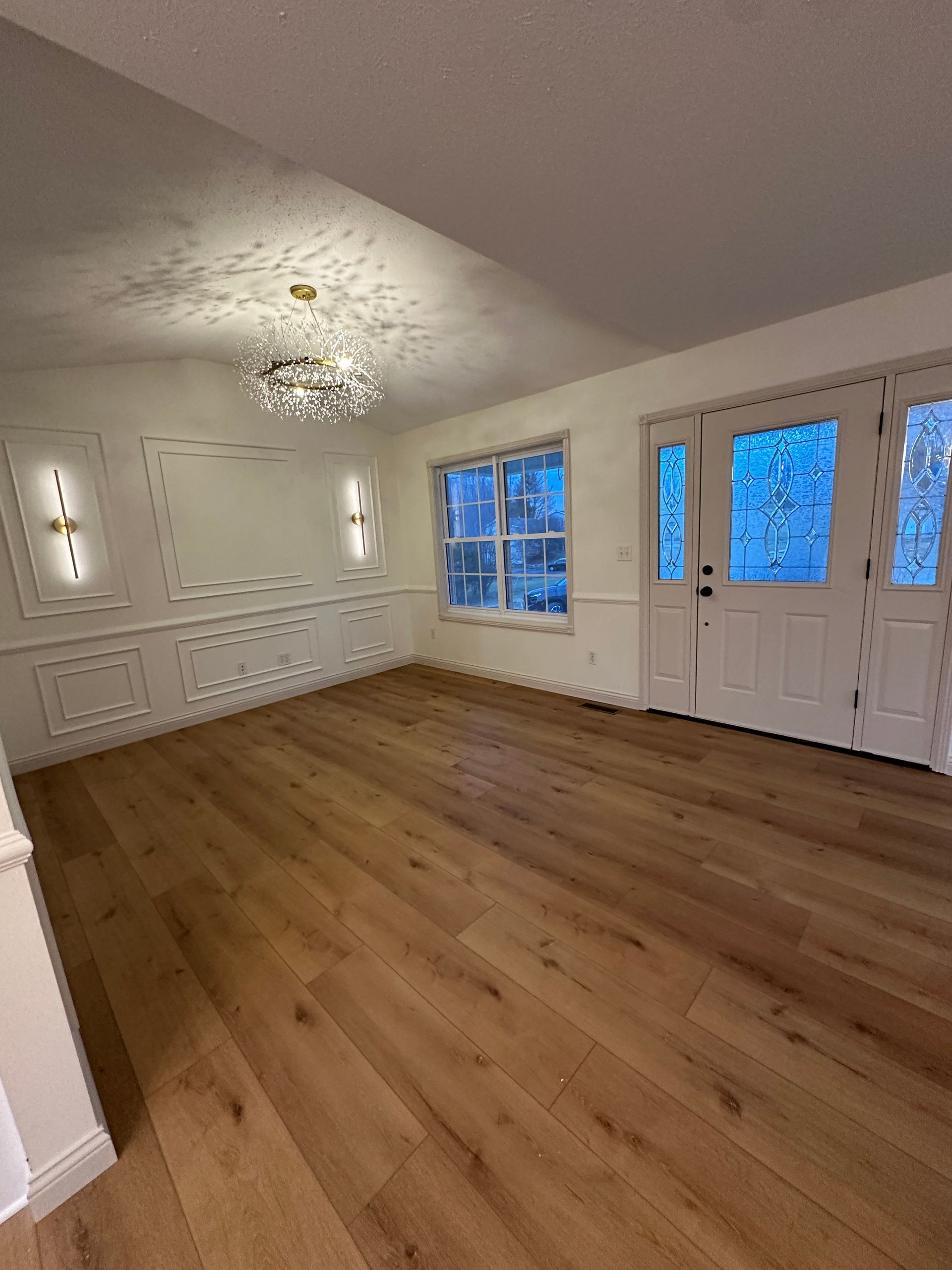 Empty room with wood floors, white walls, and a decorative ceiling light.