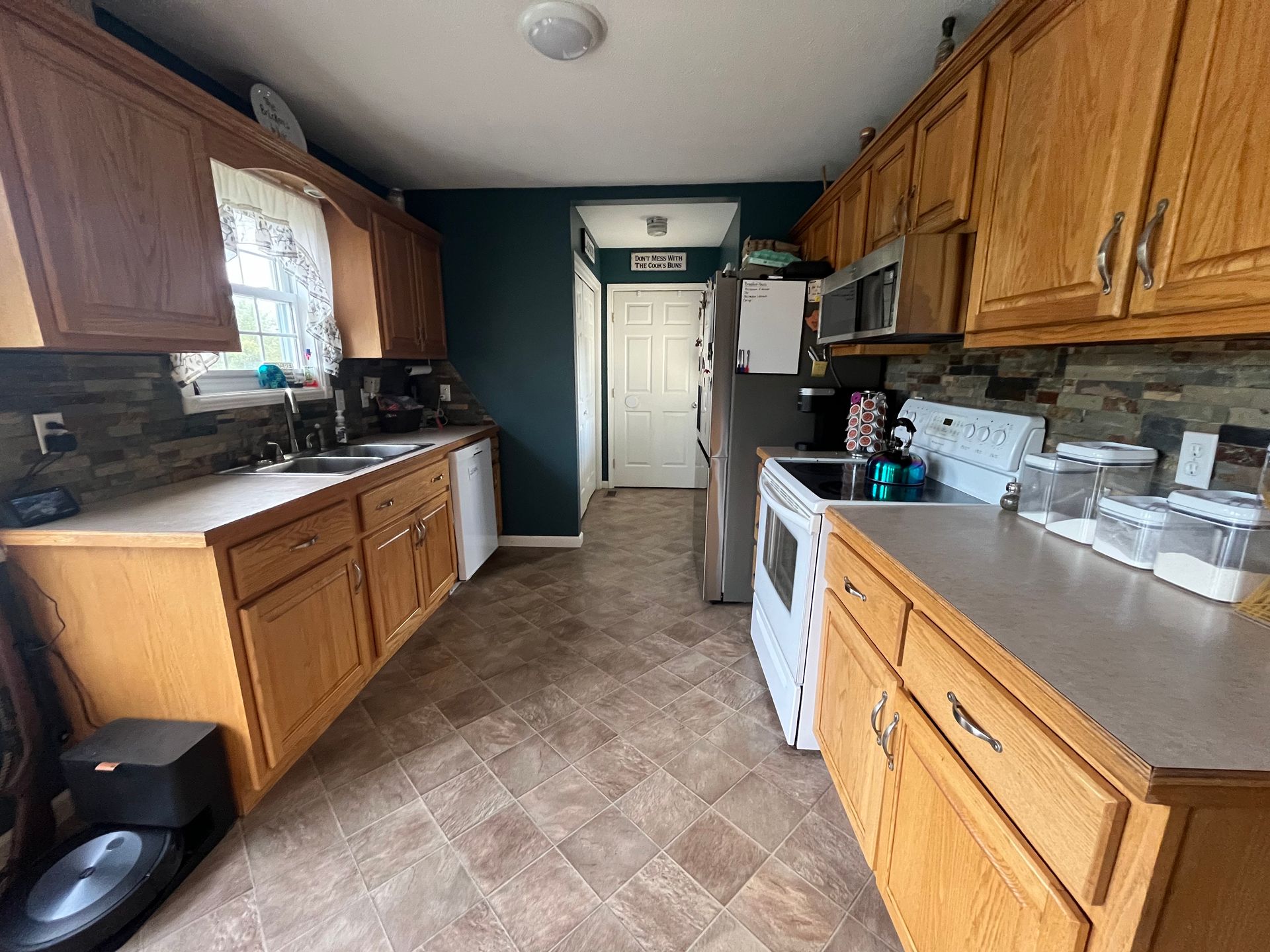 Kitchen with wood cabinets, white appliances, and dark blue accent wall.
