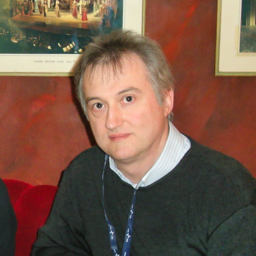 Un uomo con un cordino al collo guarda la telecamera