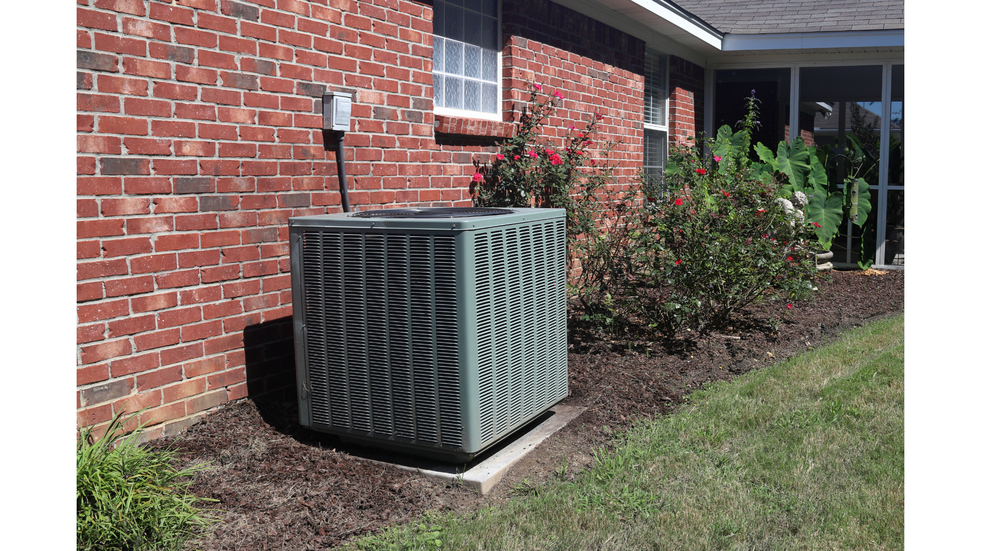 An air conditioner is sitting on the side of a brick house.