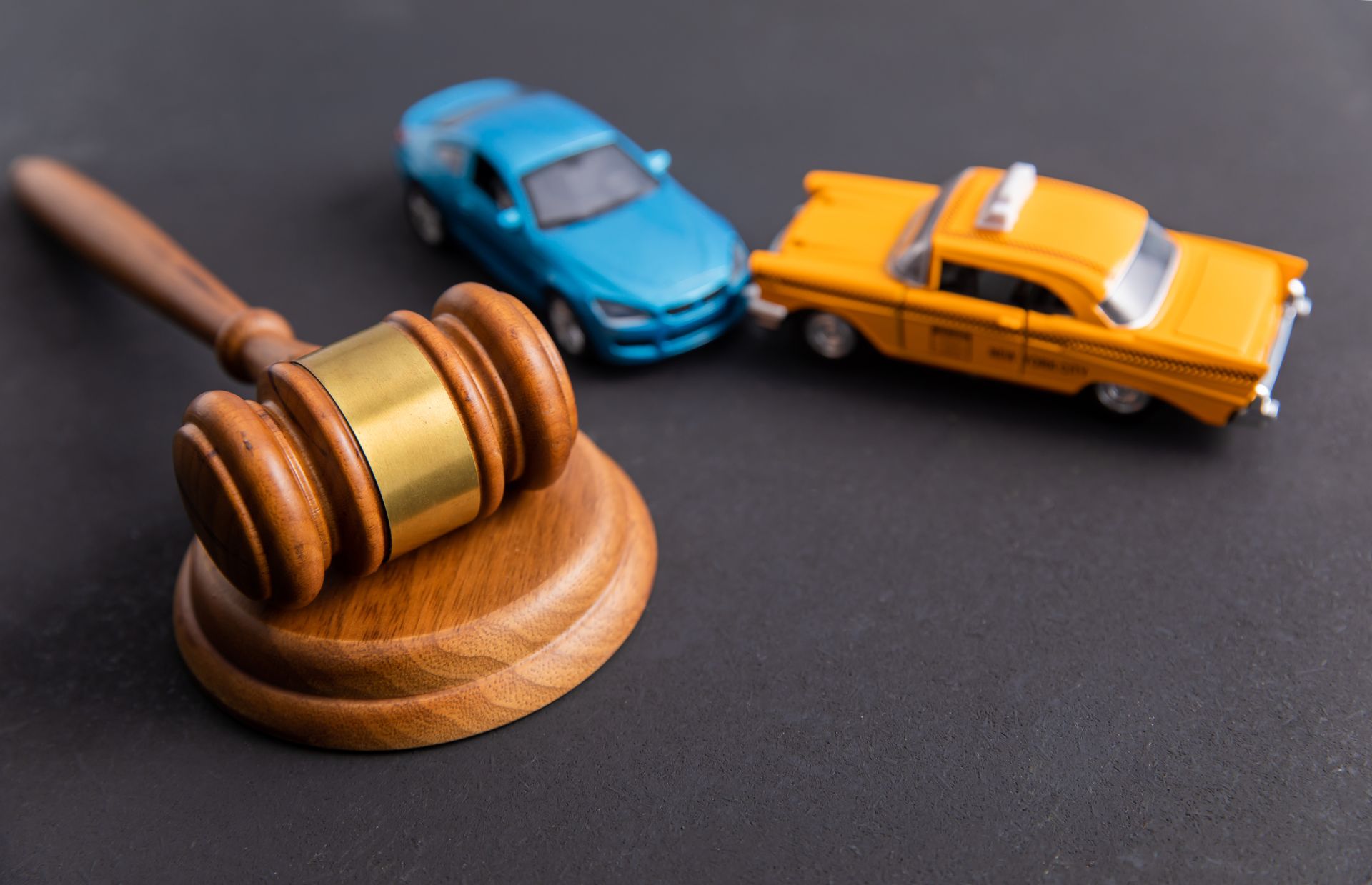 Two toy cars are sitting next to a wooden judge 's gavel.