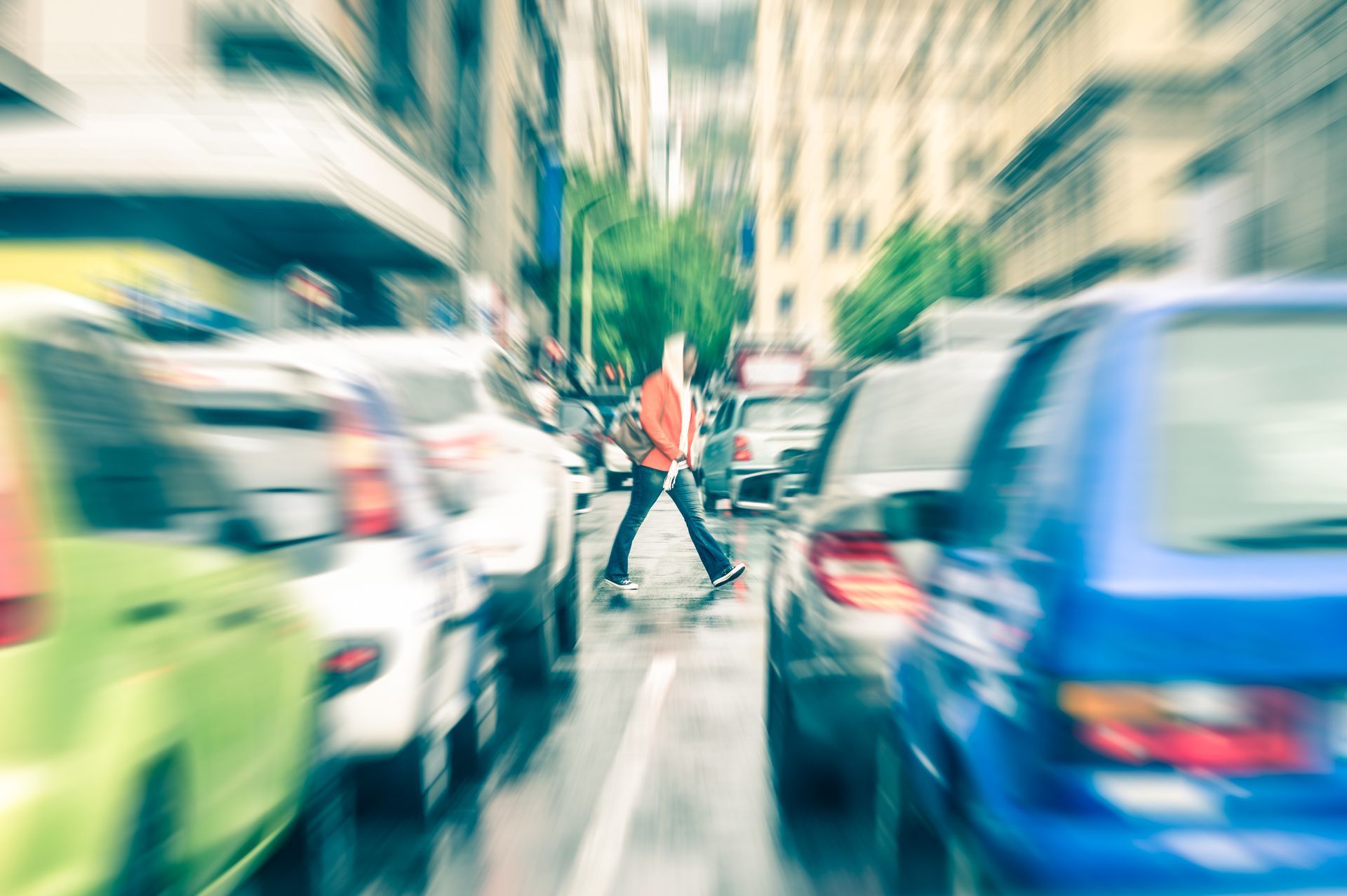 Pedestrian crossing street amidst blurred traffic.