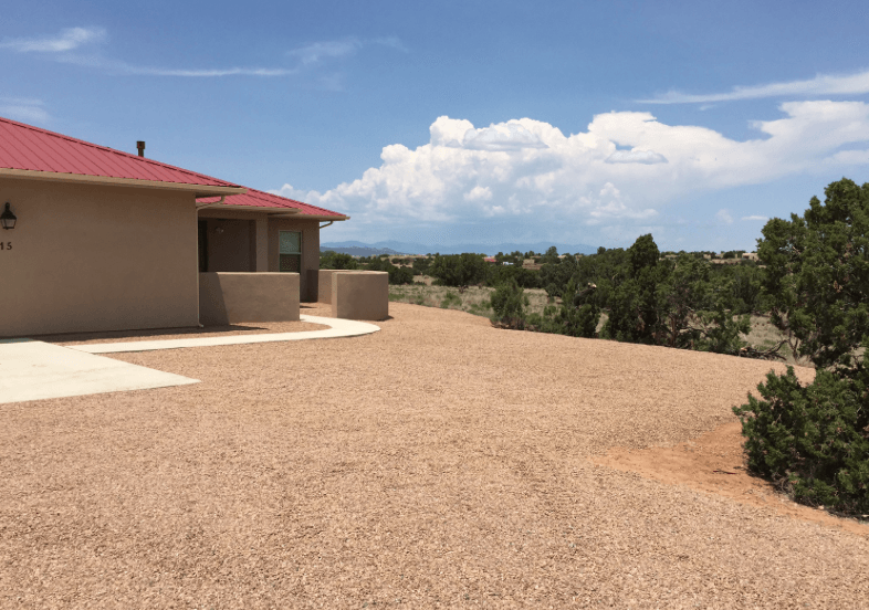 A house with a red roof and a gravel driveway