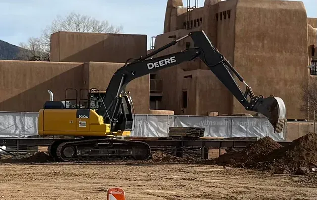 A deere excavator is digging a hole in a construction site.
