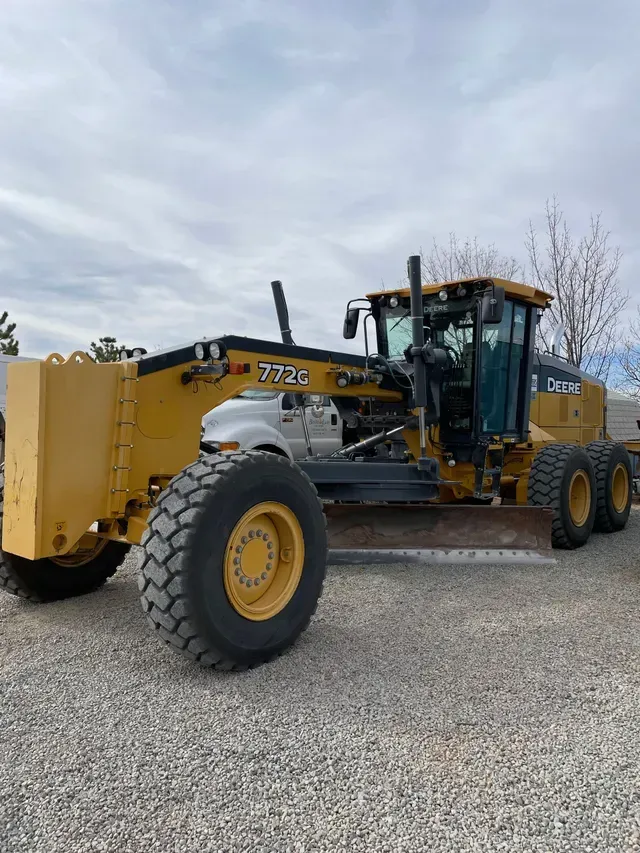 A yellow and black tractor is parked on a gravel road.