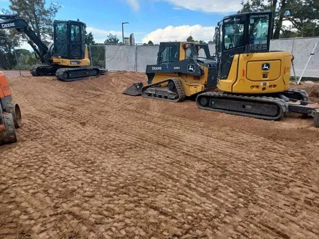 Two construction vehicles are parked in a dirt field.