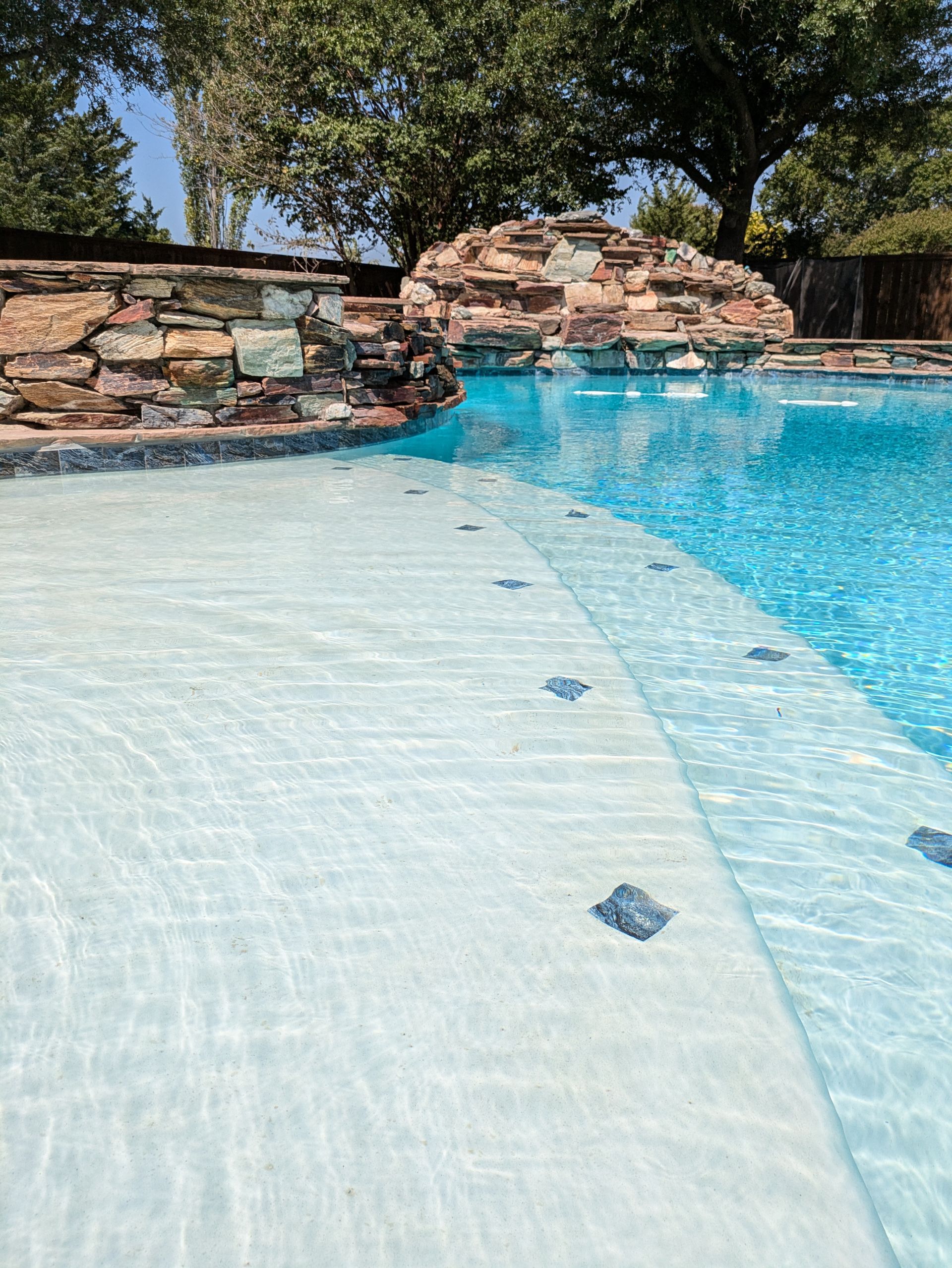 A large swimming pool with a large rock in the background