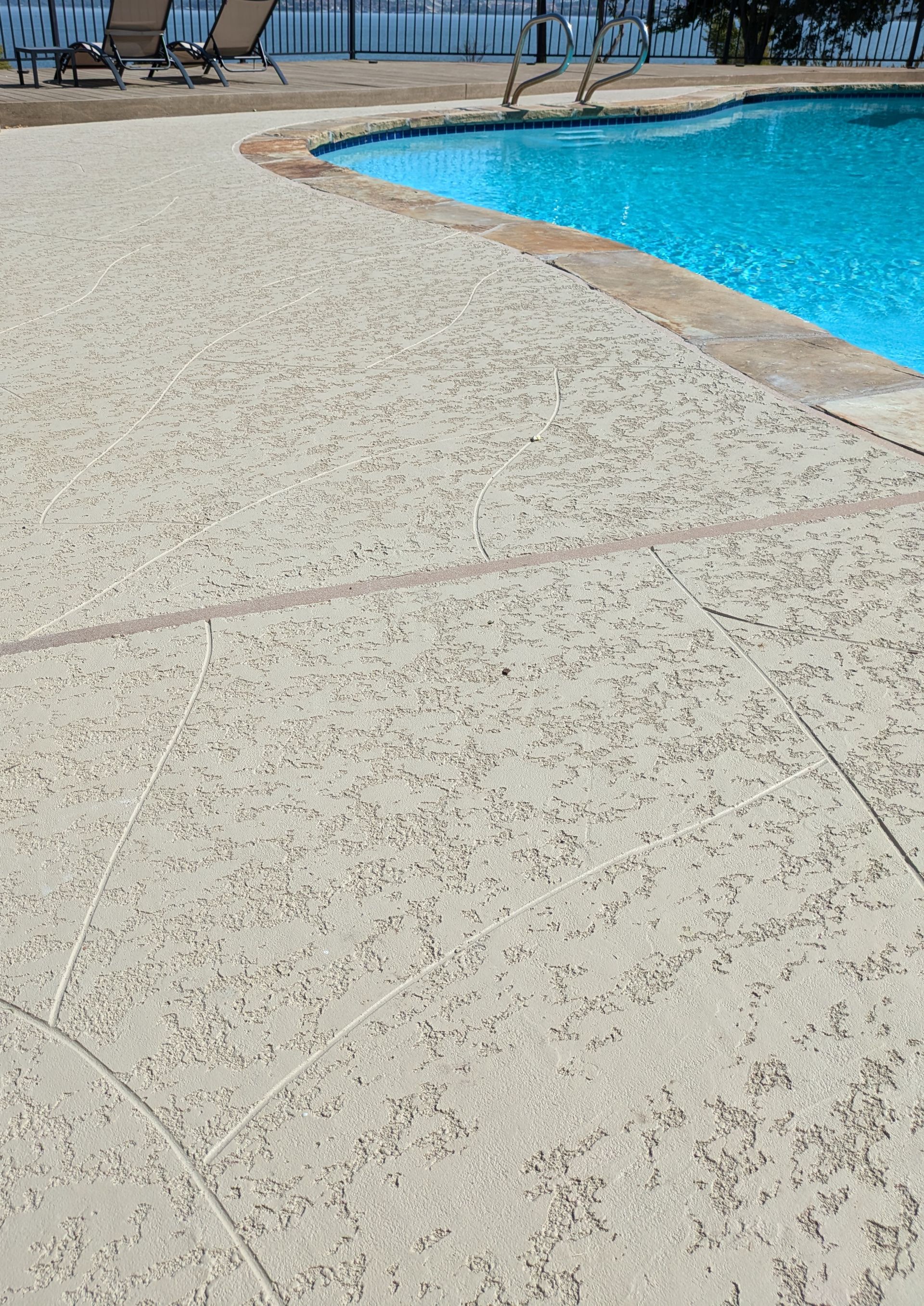 A large swimming pool with a concrete deck surrounding it