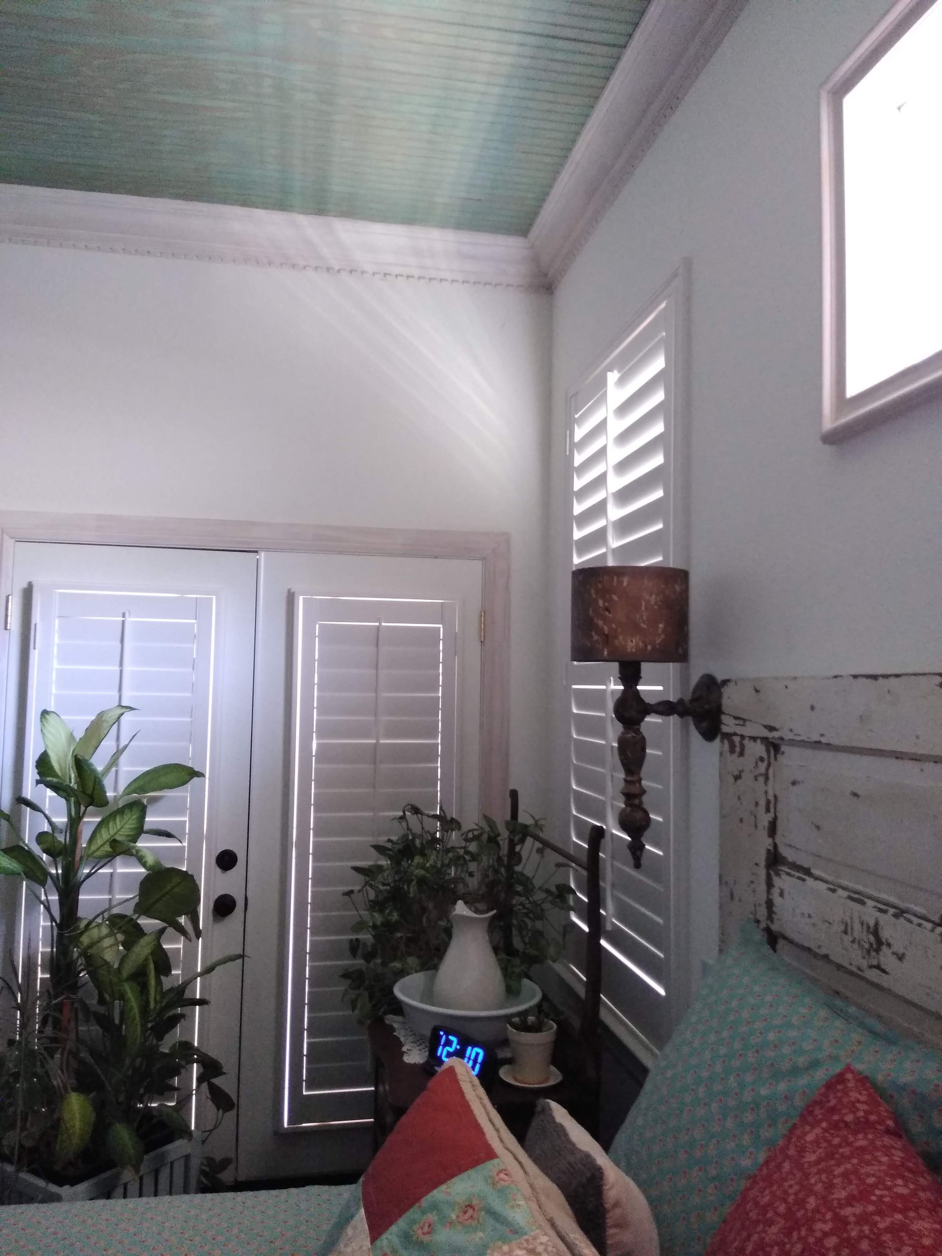 A bedroom with a bed and a lamp on the wall