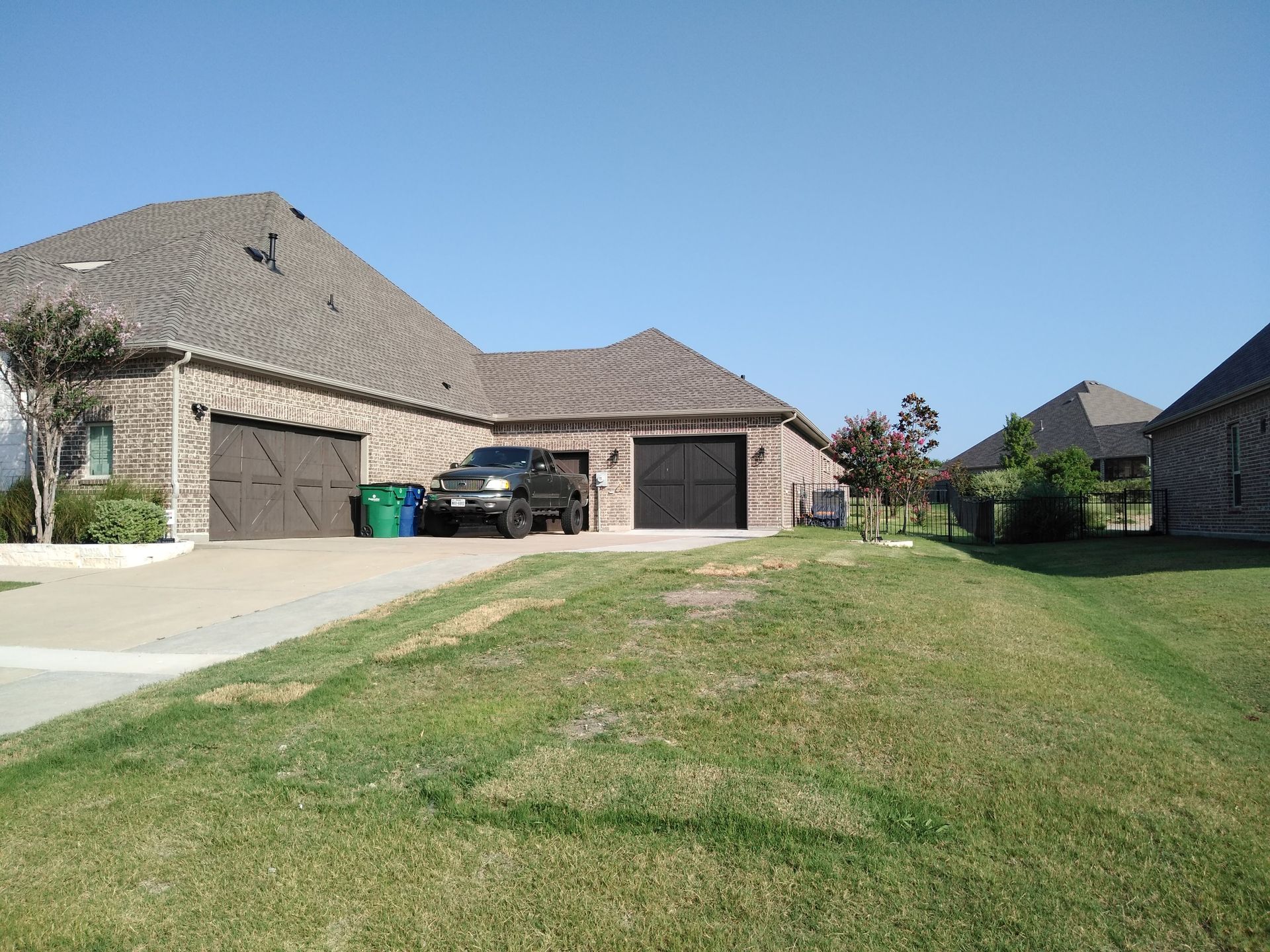 A black truck is parked in front of a brick house.