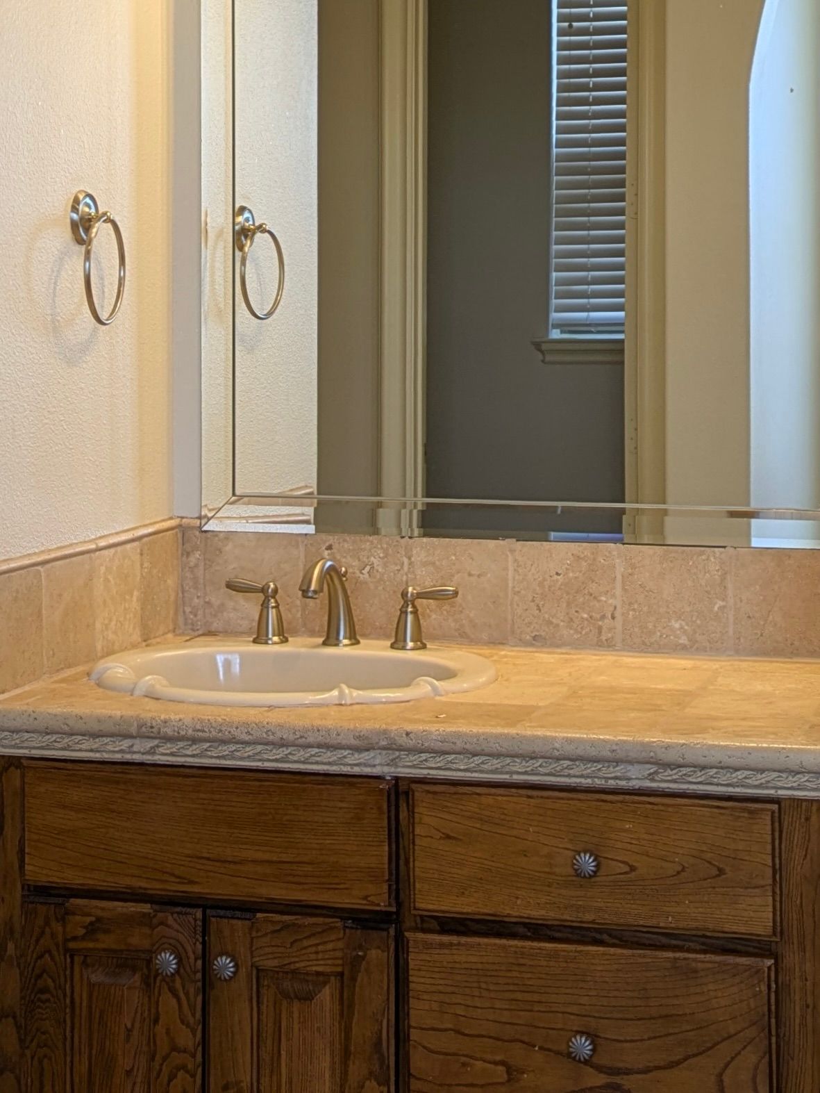 Bathroom vanity with a sink, mirror, and wooden cabinets.