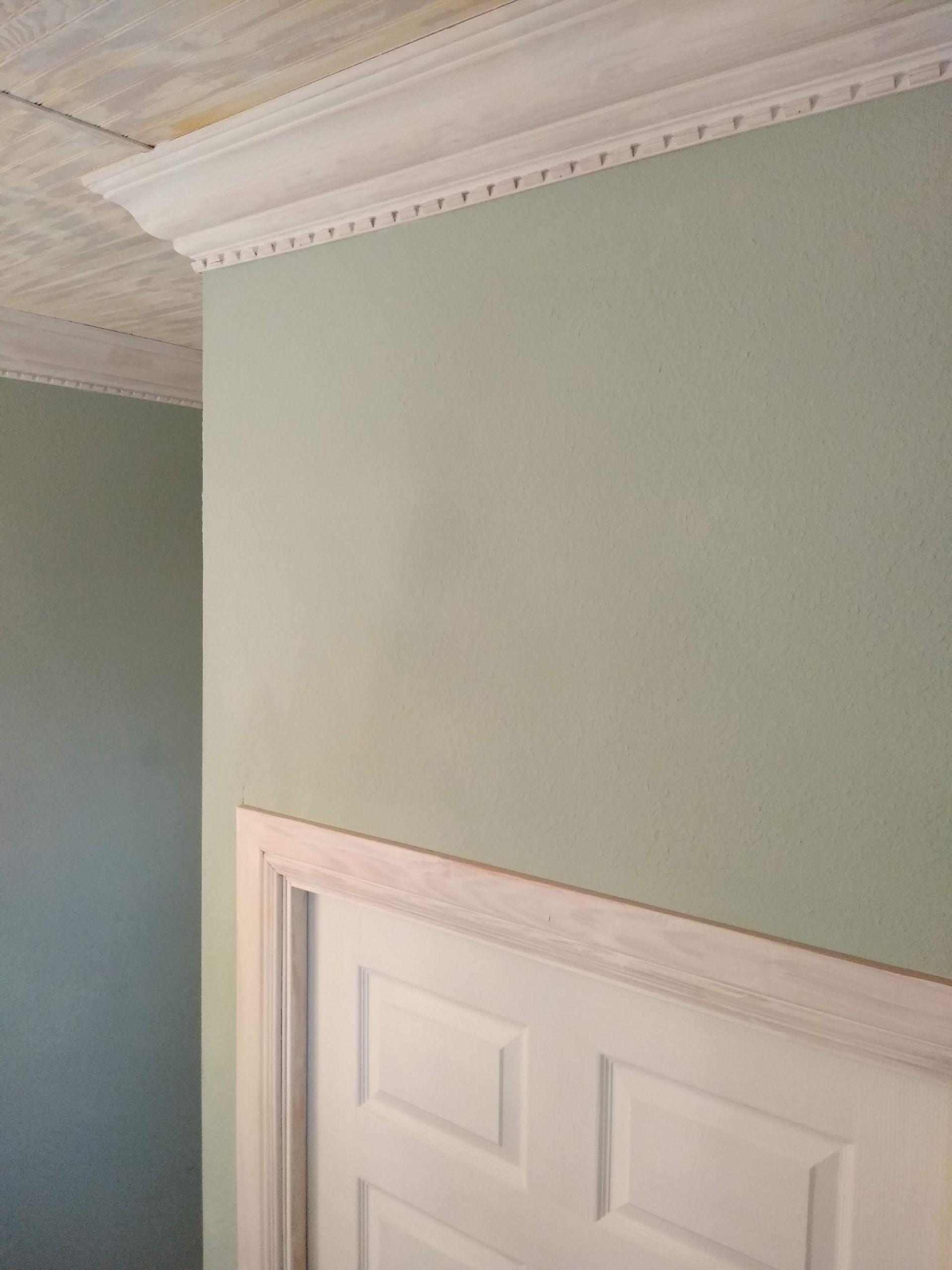 There is a door in the middle of a room with green walls.