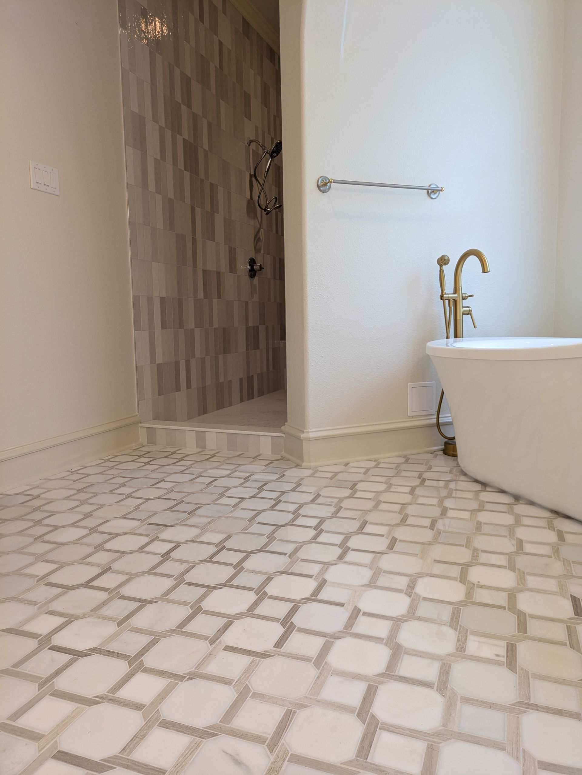 Bathroom with patterned floor tiles, walk-in shower, and freestanding tub.