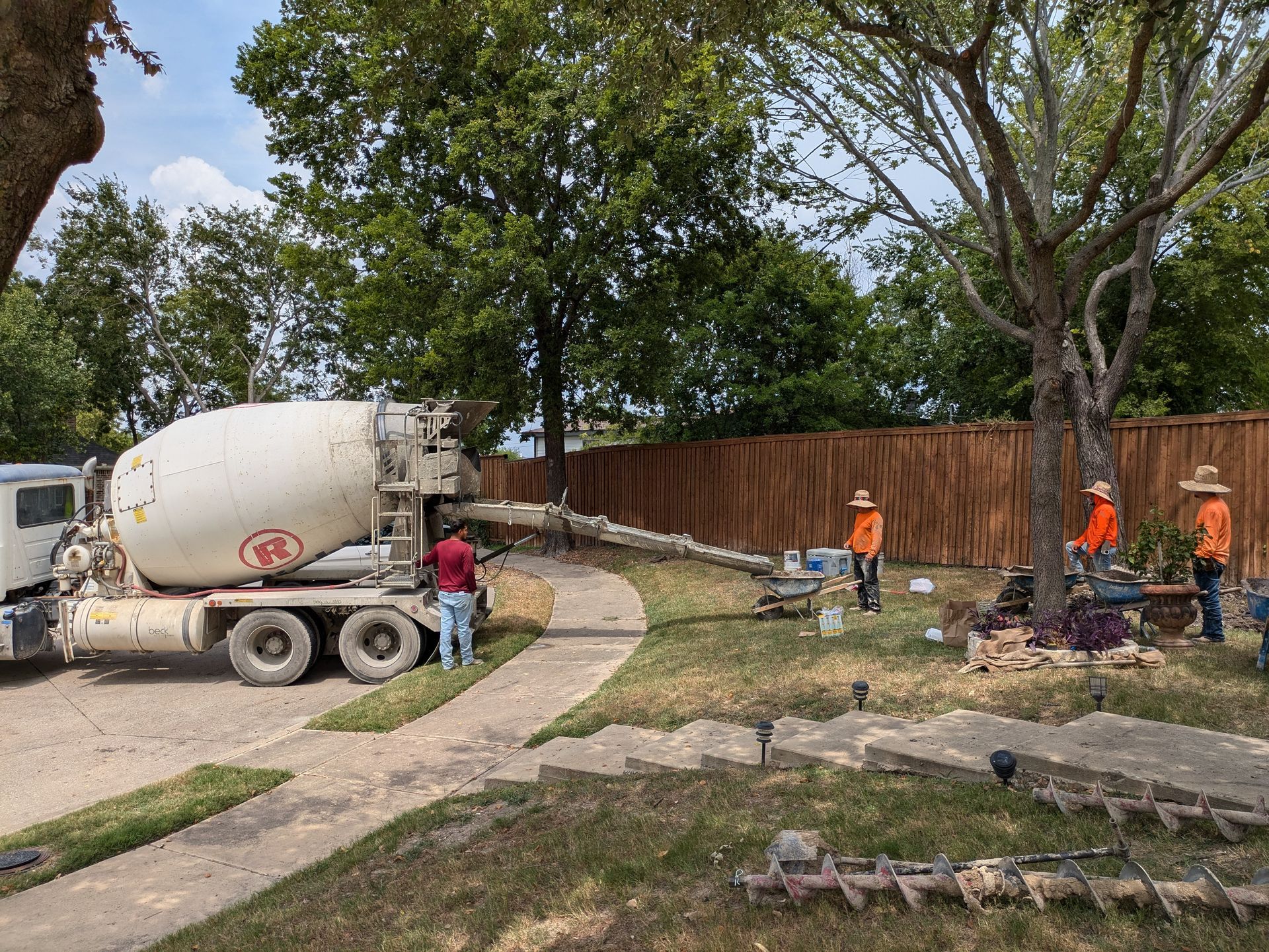 A concrete mixer truck is pouring concrete into a driveway.