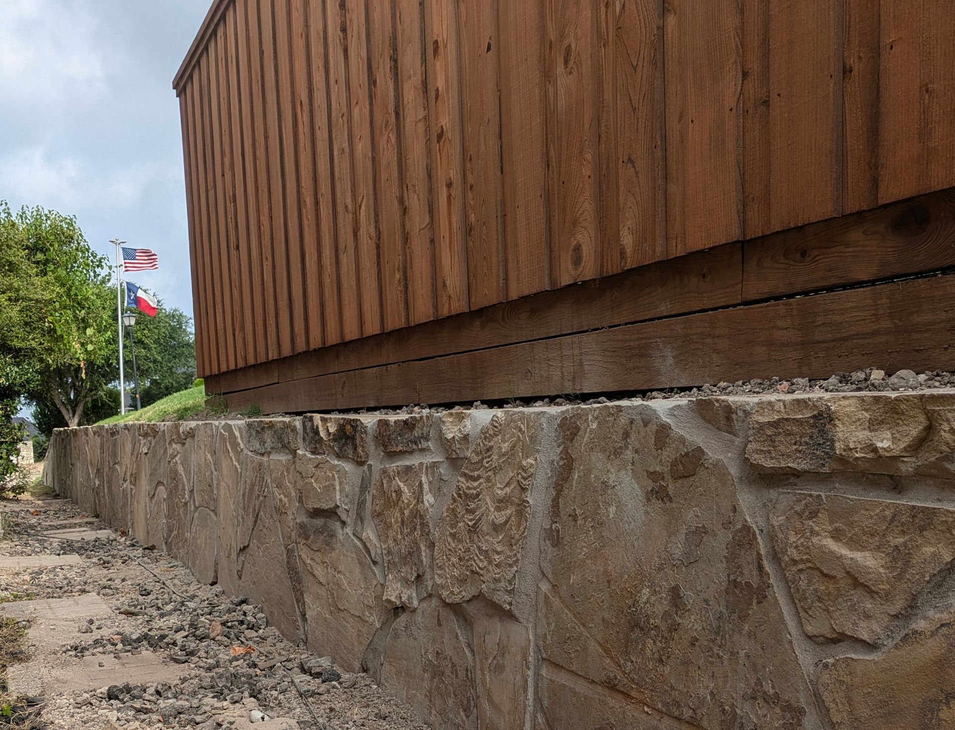 A wooden fence is sitting on top of a stone wall.