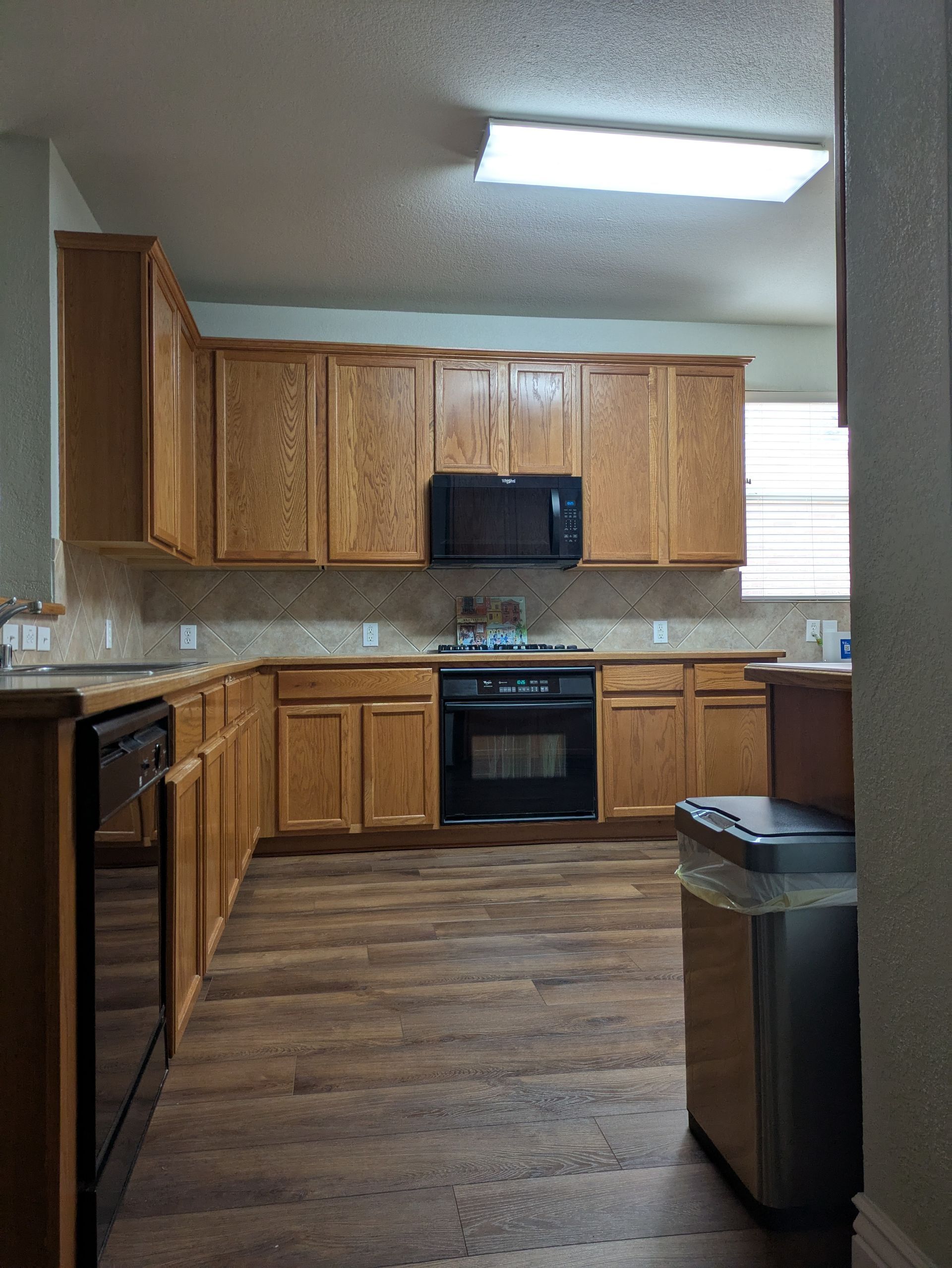 Kitchen with wood cabinets, black appliances, and laminate flooring.