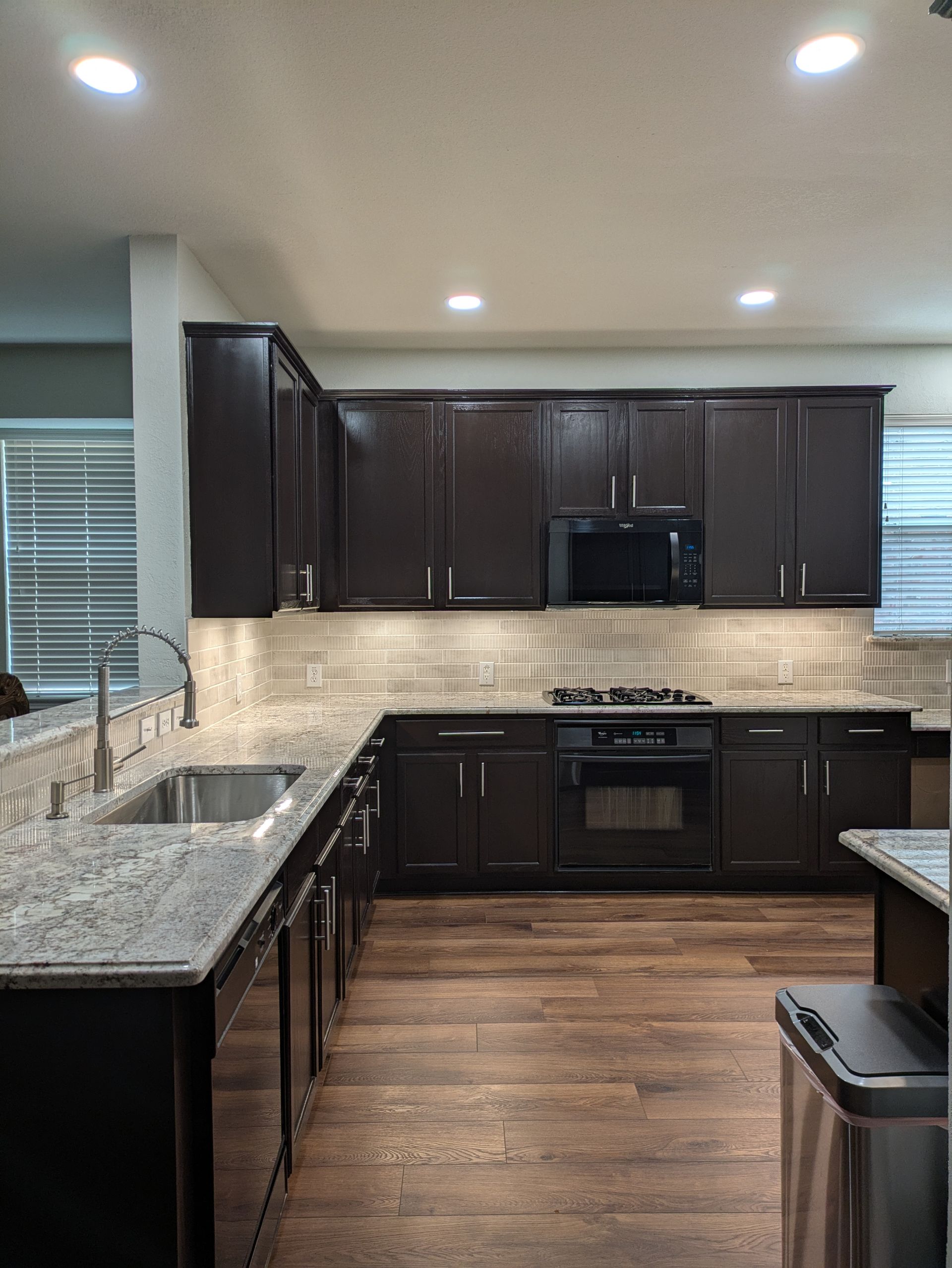 Dark wood kitchen cabinets, granite countertops, stainless steel appliances, and wood floor.
