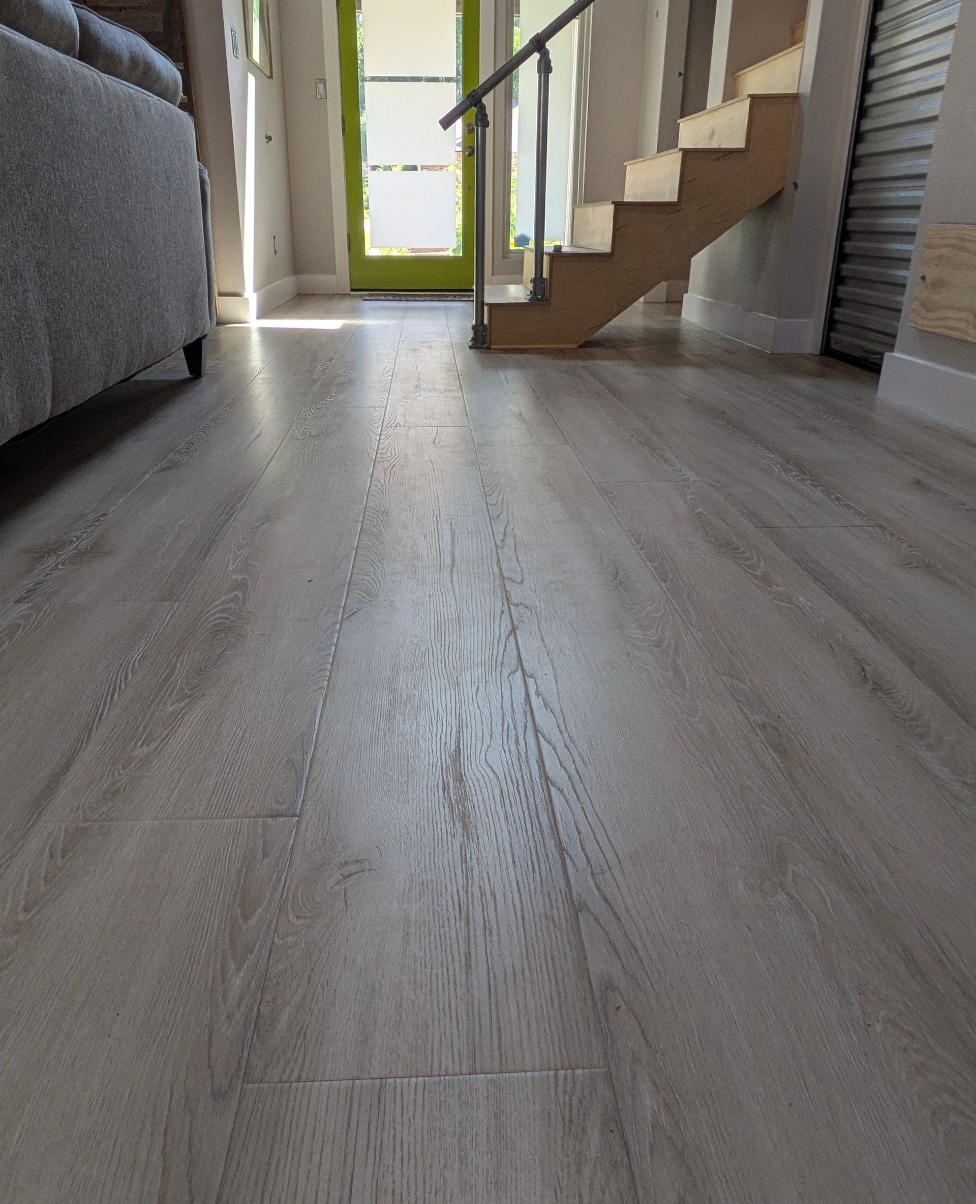 A living room with a wooden floor and stairs.
