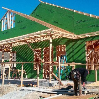 A man is standing in front of a house under construction.
