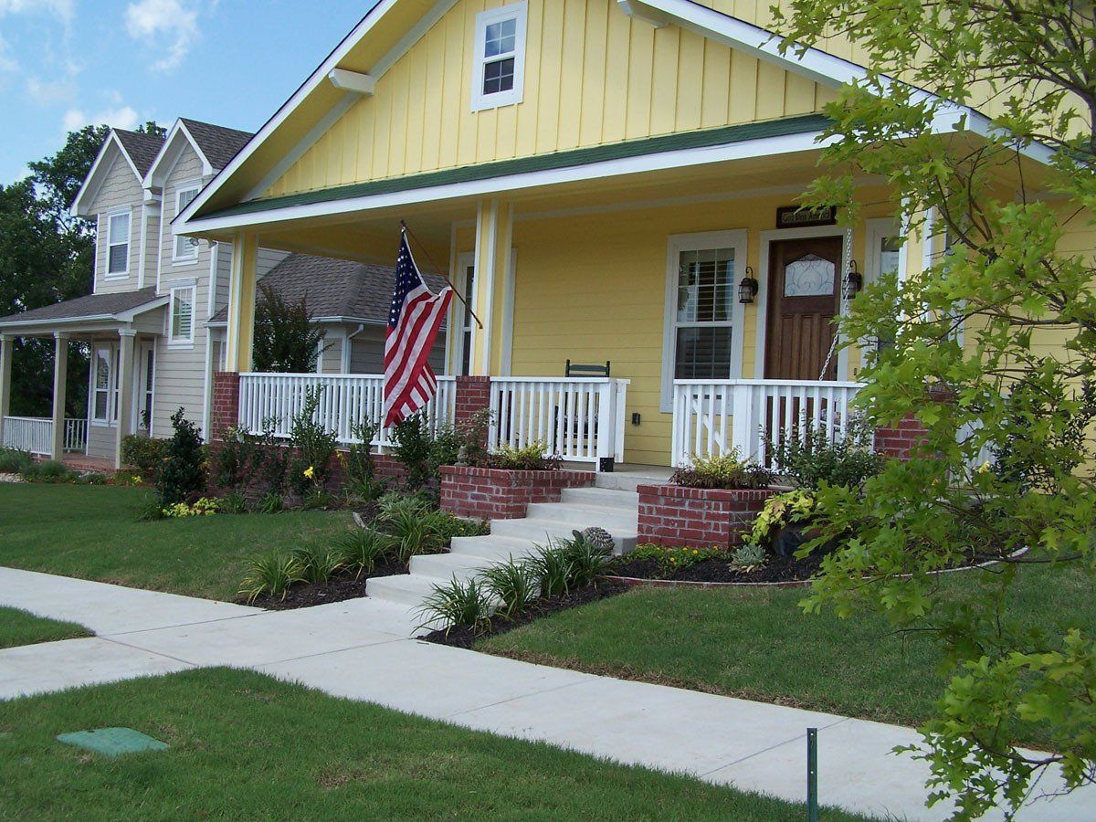 A yellow house with an american flag on the porch