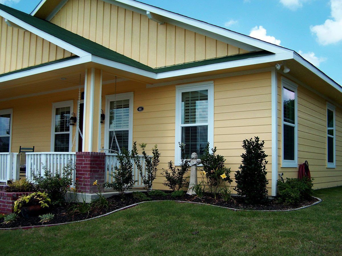 A yellow house with a green roof and white trim