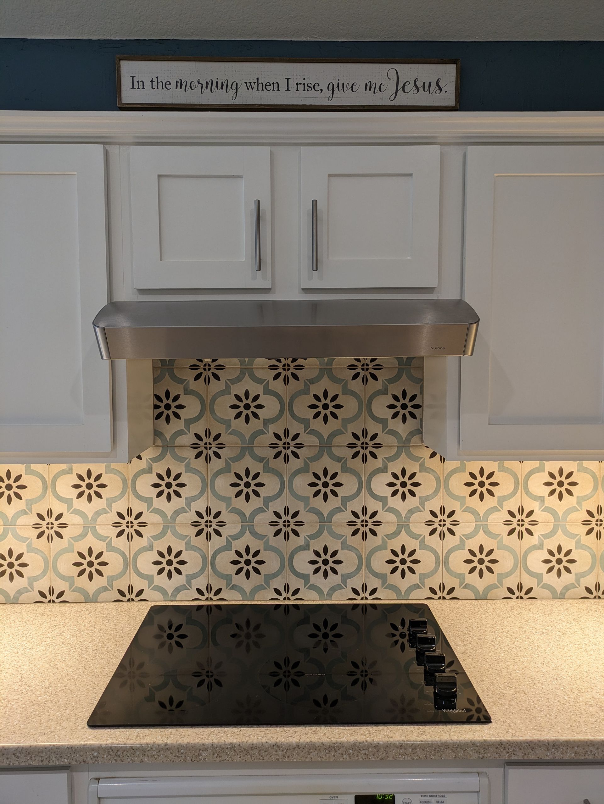 A kitchen with white cabinets and a stove top oven