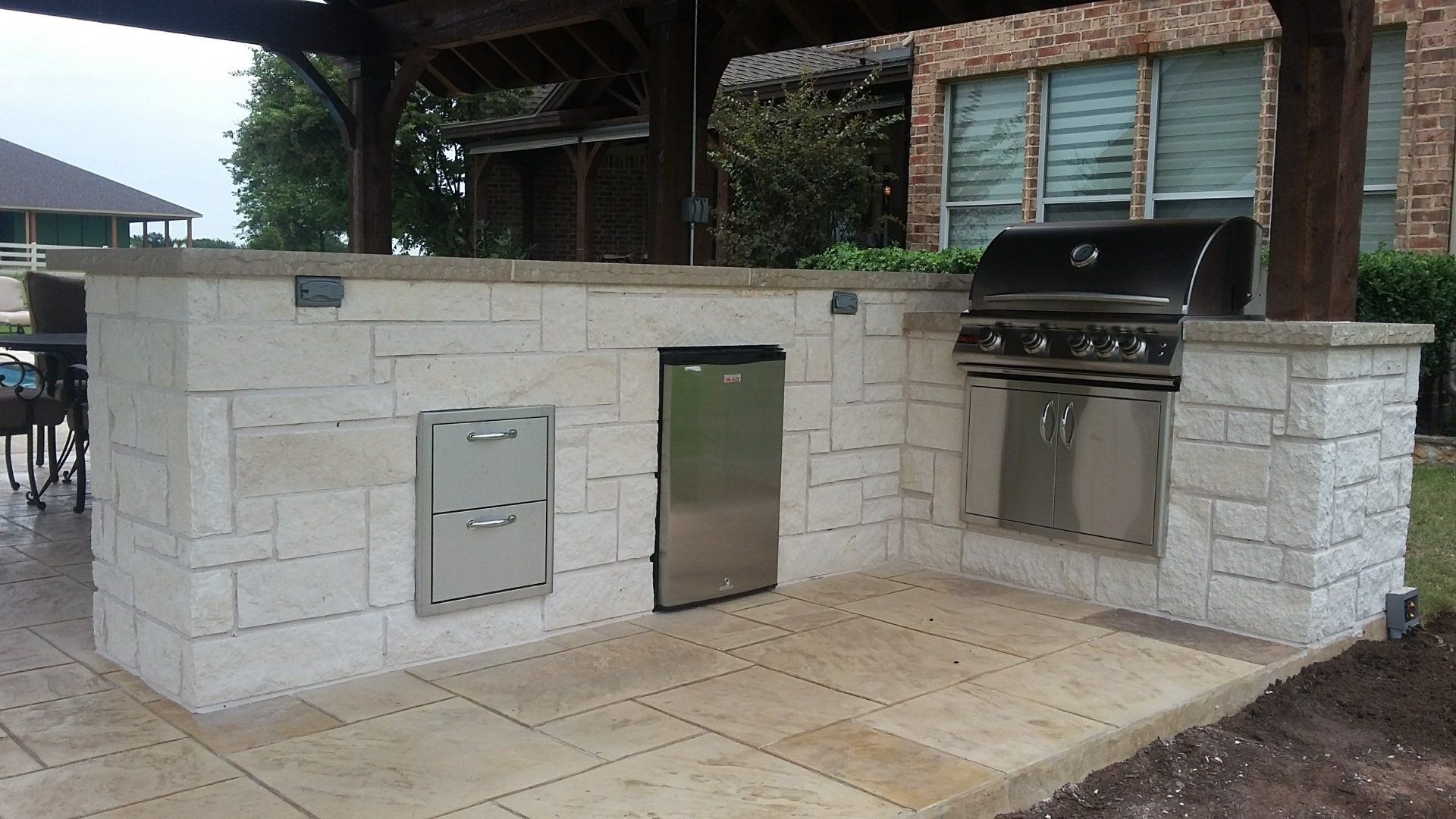 An outdoor kitchen with a grill and a dishwasher